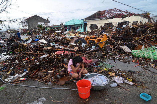 LEYTE, PHILIPPINES - NOVEMBER 12:  A girl pauses while washing clothes amongst the debris in an area devastated by Typhoon Haiyan on November 12, 2013 in Leyte, Philippines. Four days after the Typhoon Haiyan devastated the region many have nothing left, they are without food or power and most lost their homes. Around 10,000 people are feared dead in the strongest typhoon to hit the Philippines this year.  (Photo by Dondi Tawatao/Getty Images)