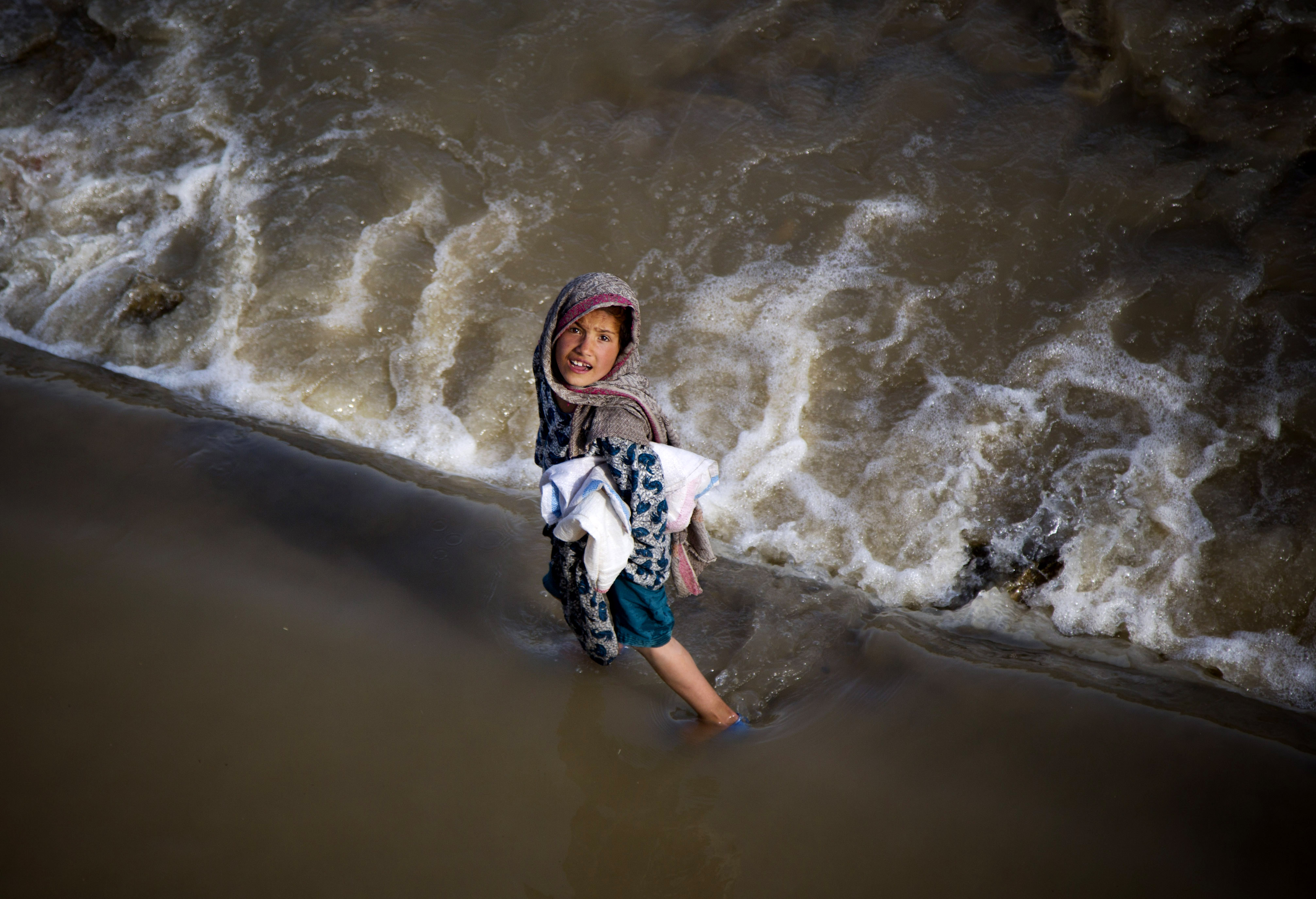 An Afghan girl takes a short cut through a streaming river on the outskirts of Kabul, Afghanistan, Wednesday, May 15, 2013. Temperatures in Kabul have risen to 27 degrees Celsius (82 degrees Farhreinheit), bringing children out to play in streams. (AP Photo/Anja Niedringhaus)