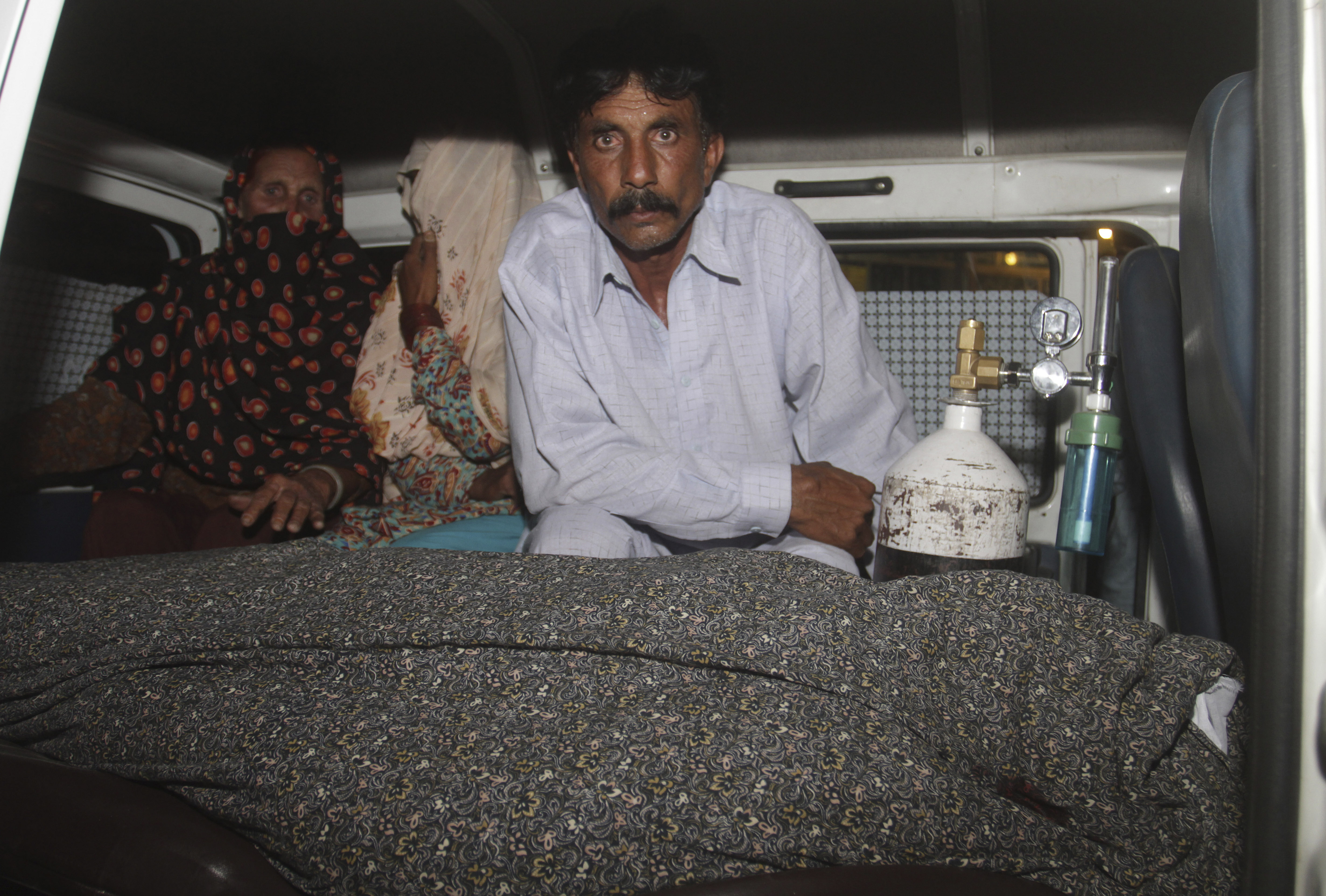 Mohammad Iqbal, right, husband of Farzana Parveen, 25, sits in an ambulance next to the body of his pregnant wife who was stoned to death by her own family, in Lahore, Pakistan, Tuesday, May 27, 2014. Nearly 20 members of the woman's family, including her father and brothers, attacked her and her husband with batons and bricks in broad daylight before a crowd of onlookers in front of the high court of Lahore, police investigator Rana Mujahid said. (AP Photo/K.M. Chaudary)