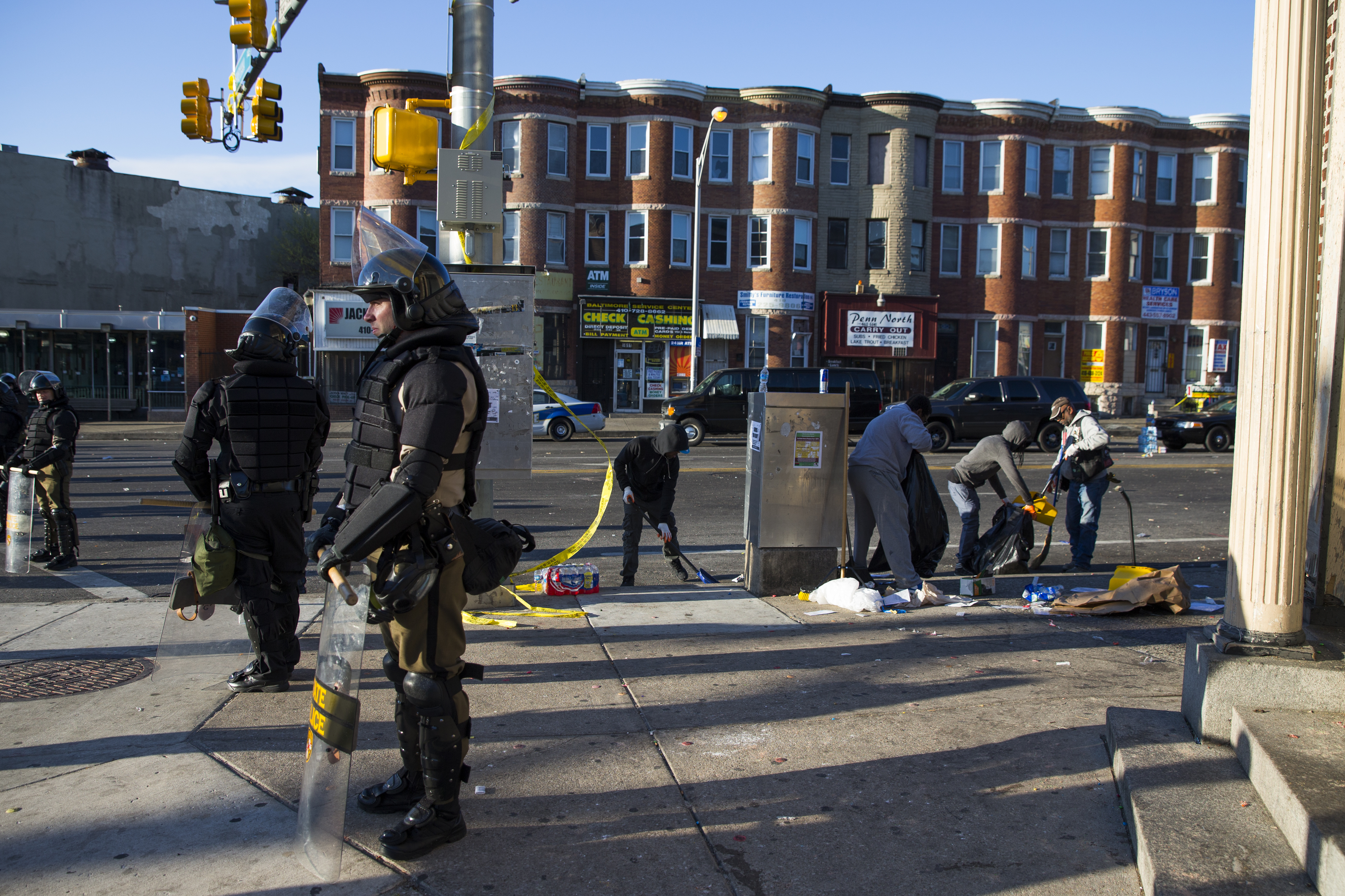 Maryland state troopers stand guard, Tuesday, April 28, 2015, as residents clean up after an evening of riots following the funeral of Freddie Gray on Monday, in Baltimore. (AP Photo/Evan Vucci)