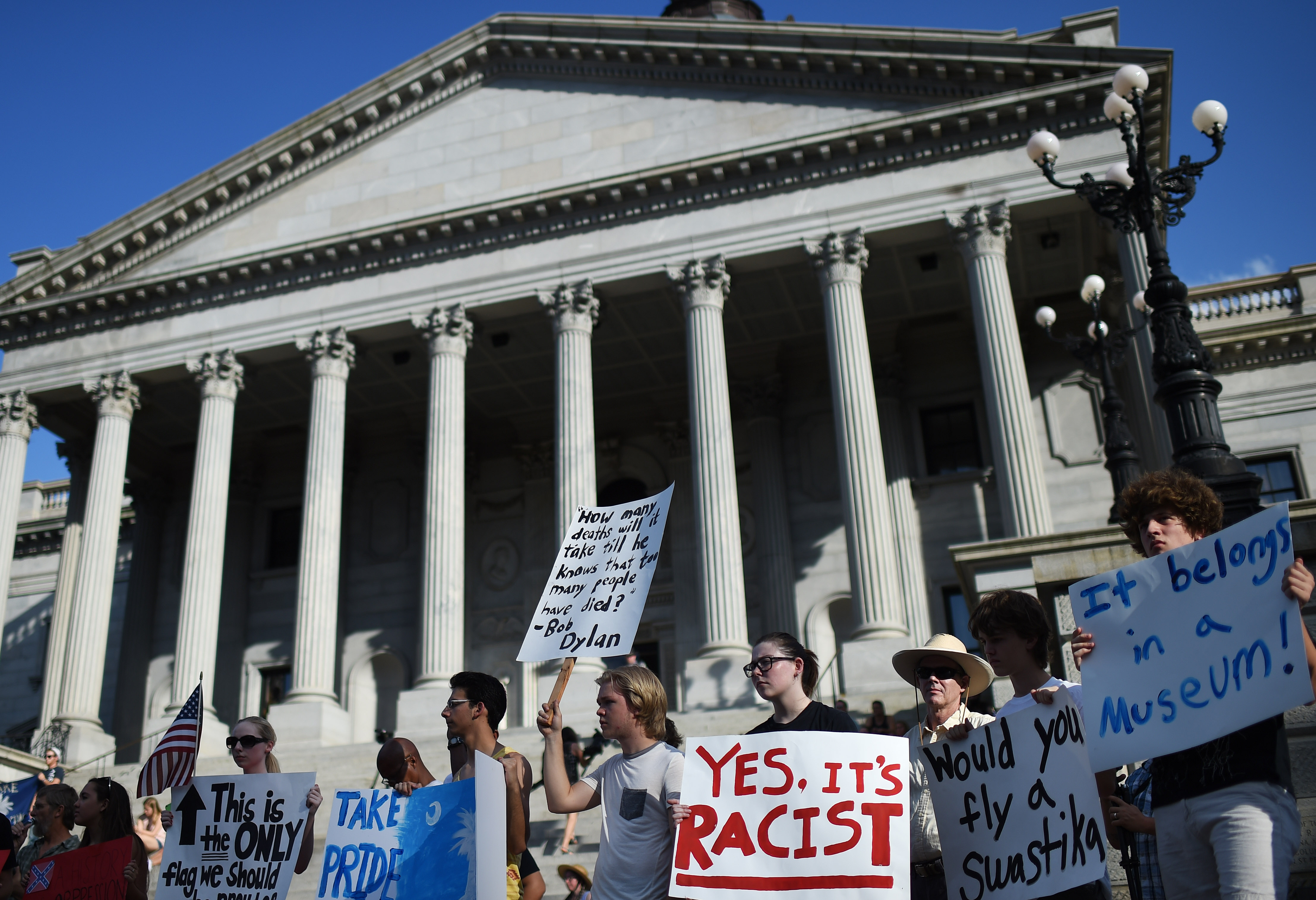 Protesters stand on the South Carolina Statehouse steps during a rally to take down the Confederate flag, Saturday, June 20, 2015, in Columbia, S.C. Rep. Doug Brannon, R-Landrum, said it's past time for the Confederate flag to be removed from South Carolina's Statehouse grounds after nine people were killed at the Emanuel A.M.E. Church shooting. (AP Photo/Rainier Ehrhardt)