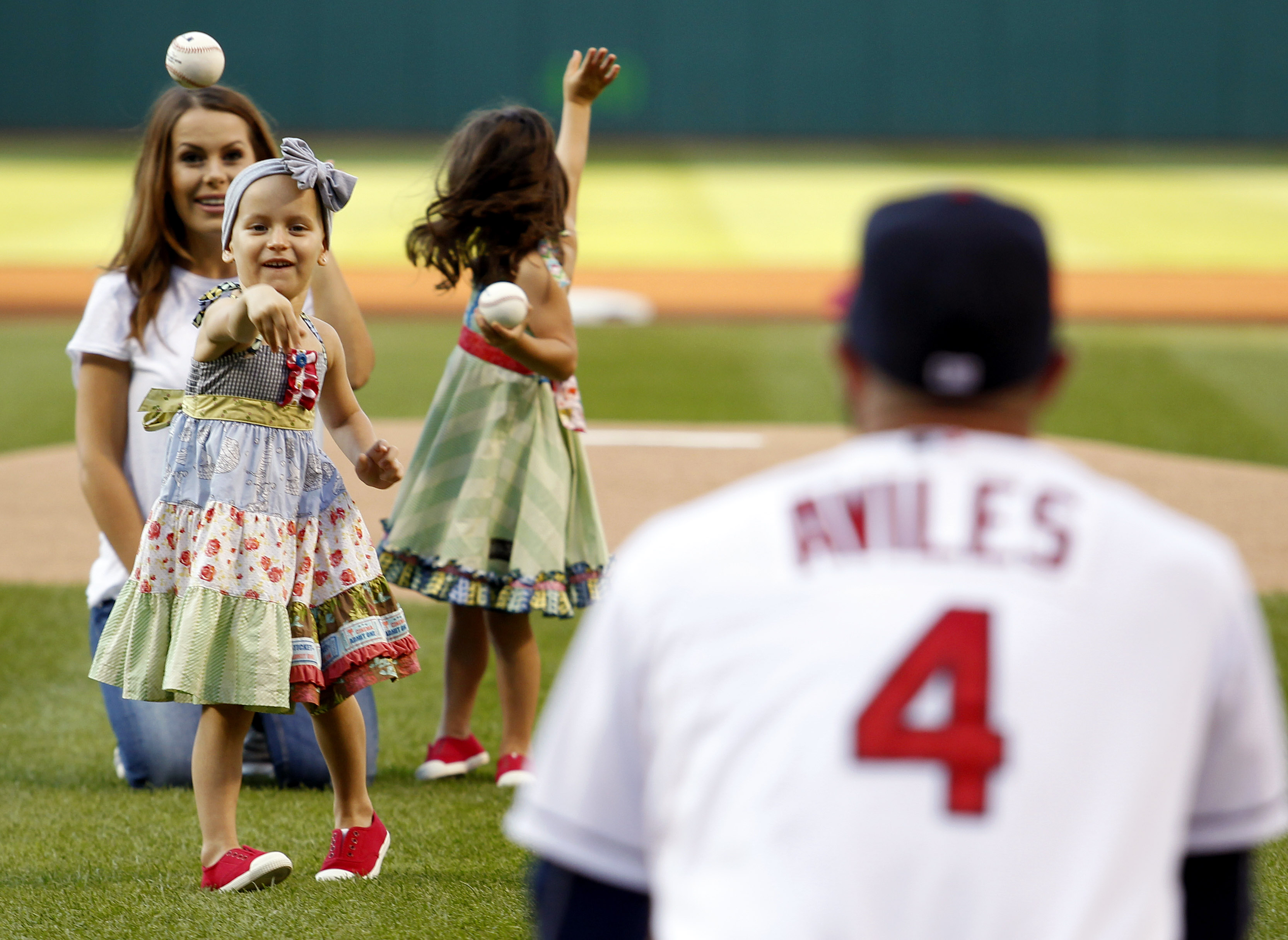 Cleveland Indians' Mike Aviles catches the ceremonial first pitch from his daughter Adriana as his wife, Jessy, watches prior to the Indians' baseball game against the New York Yankees on Thursday, Aug.13, 2015, in Cleveland. (AP Photo/Aaron Josefczyk