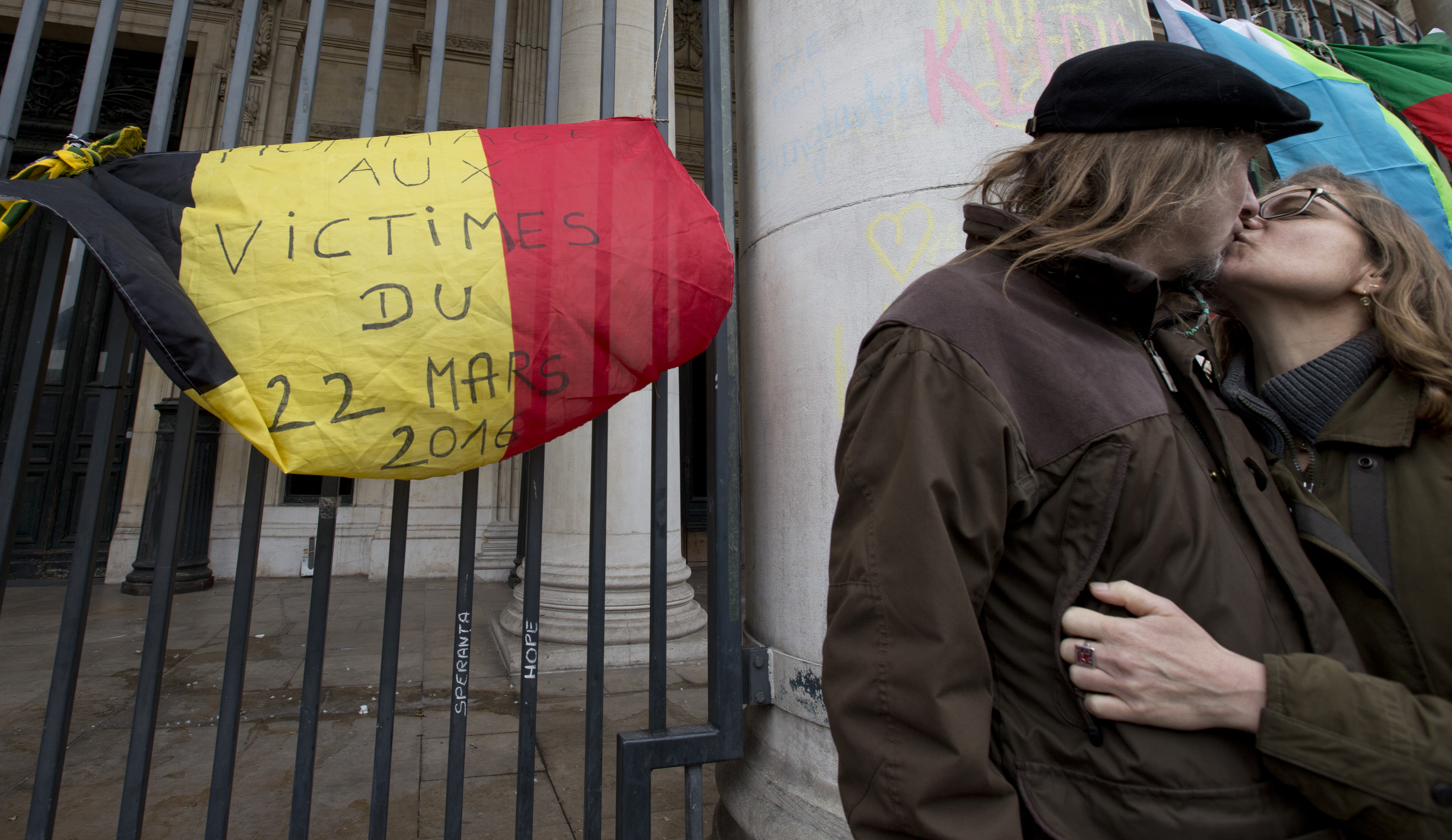 A couple kissed next to a Belgian flag reading "Homage to the victims of 22 March 2016" as people mourned for the victims of the bombings at the Place de la Bourse in the center of Brussels, Belgium, Thursday, March 24, 2016. The Islamic State group has trained at least 400 fighters to target Europe in deadly waves of attacks, deploying interlocking terror cells like the ones that struck Brussels and Paris with orders to choose the time, place and method for maximum carnage. (AP Photo/Peter Dejong)
