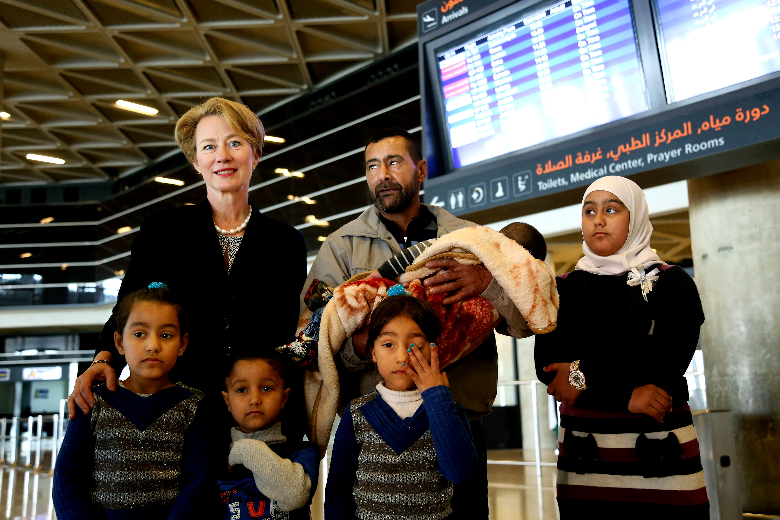U.S. Ambassador to Jordan Alice Wells, top left, poses for a photo with Syrian refugee Ahmad al-Abboud, top center, and his family at the International Airport of Amman, Jordan, Wednesday, April 6, 2016. The first Syrian family to be resettled to the U.S. under its speeded-up "surge operation" departed to the United States Wednesday from the Jordanian capital, Amman. Al-Abboud, who is being resettled with his wife and five children, said that although he is thankful to Jordan — where he has lived for three years after fleeing Syria's civil war — he is hopeful of finding a better life in the U.S. (AP Photo/Raad Adayleh)
