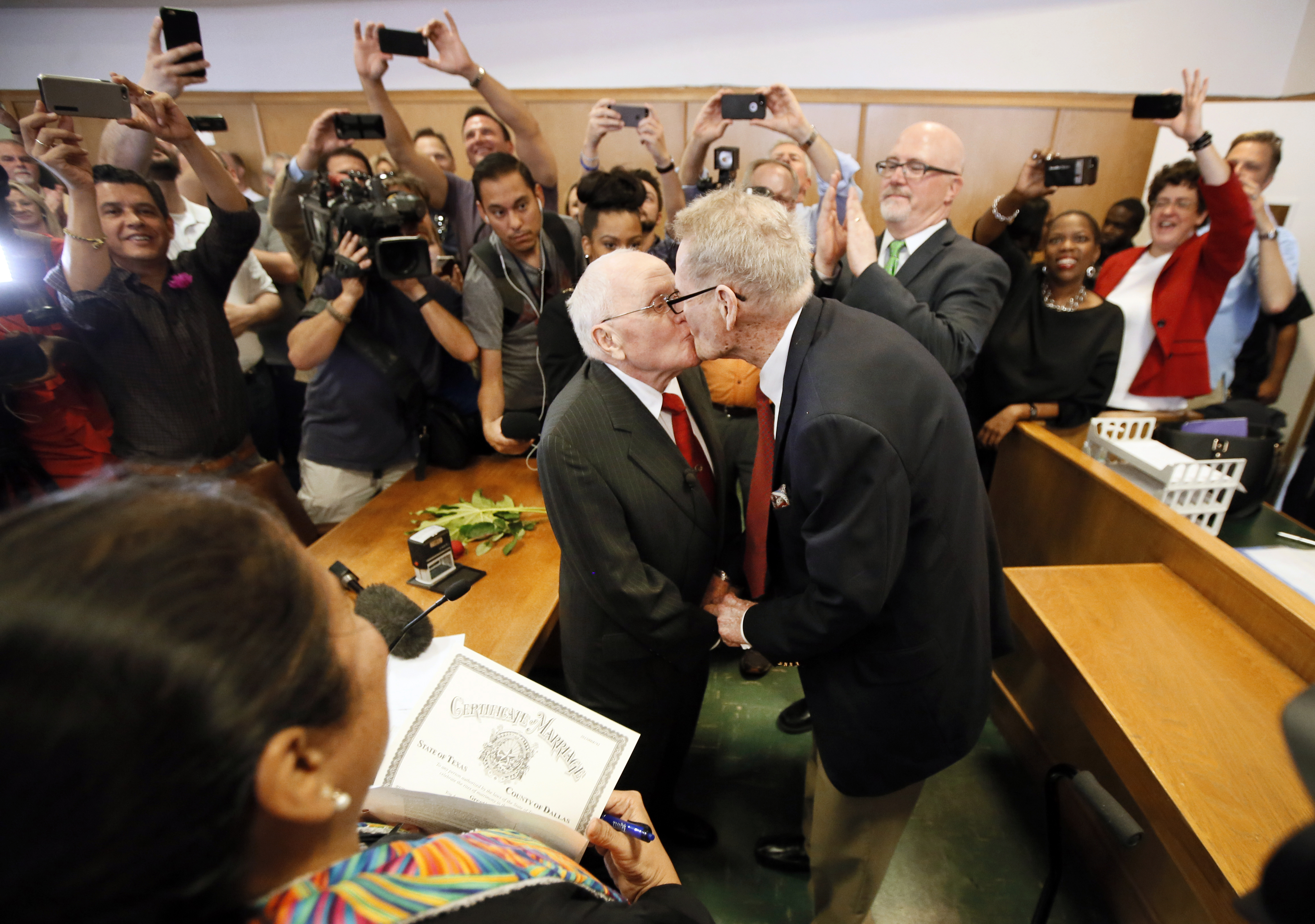 Judge Dennise Garcia, left front, watches as George Harris, center left, 82, and Jack Evans, center right, 85, kiss after being married by Judge Garcia Friday, June 26, 2015, in Dallas. Gay and lesbian Americans have the same right to marry as any other couples, the Supreme Court declared Friday in a historic ruling deciding one of the nation's most contentious and emotional legal questions. Celebrations and joyful weddings quickly followed in states where they had been forbidden. (AP Photo/Tony Gutierrez)