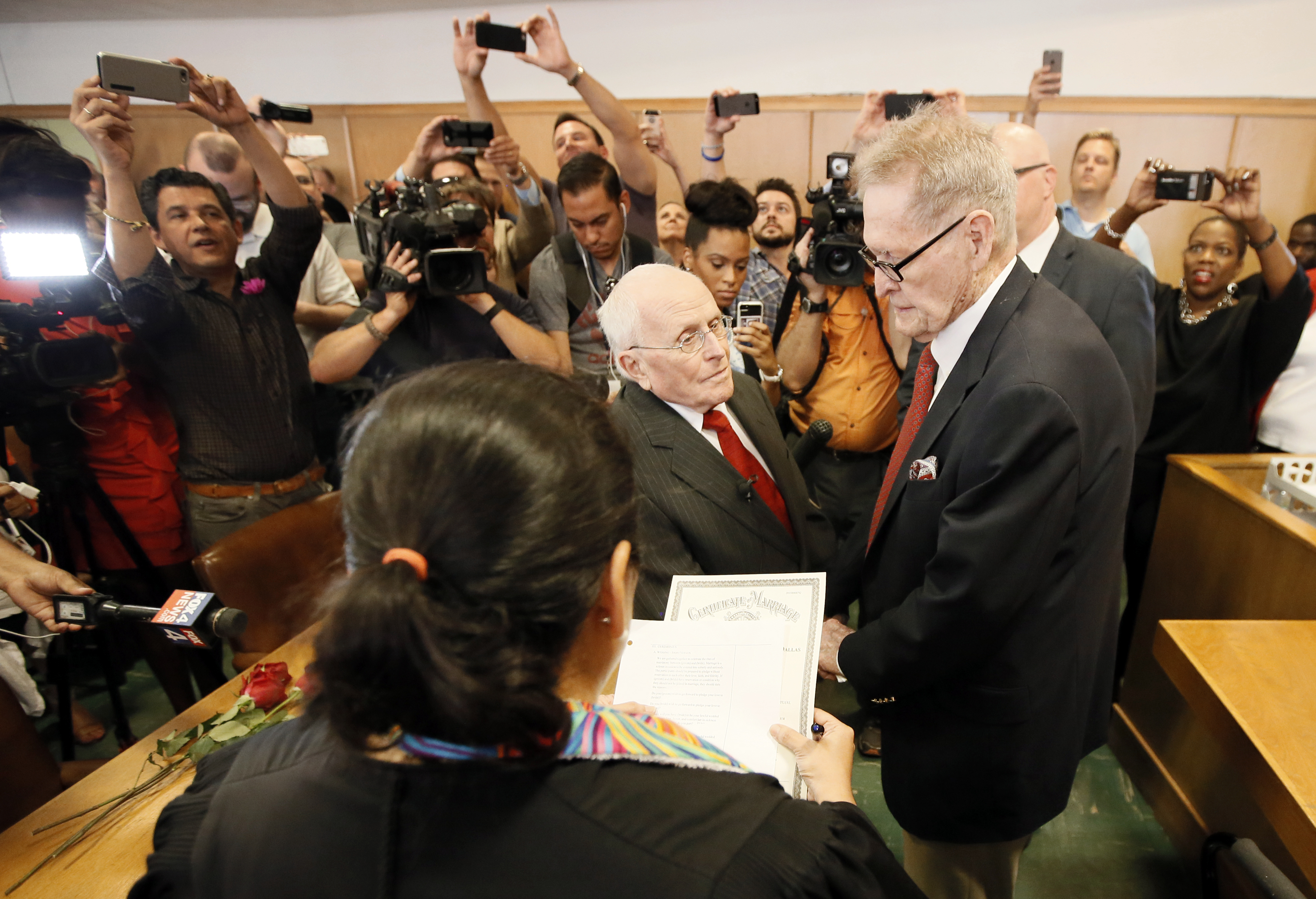 Judge Dennise Garcia, front, conducts a marriage ceremony for George Harris, center left, 82, and Jack Evans, 85, center right, Friday, June 26, 2015, in Dallas. Gay and lesbian Americans have the same right to marry as any other couples, the Supreme Court declared Friday in a historic ruling deciding one of the nation's most contentious and emotional legal questions. Celebrations and joyful weddings quickly followed in states where they had been forbidden. (AP Photo/Tony Gutierrez)