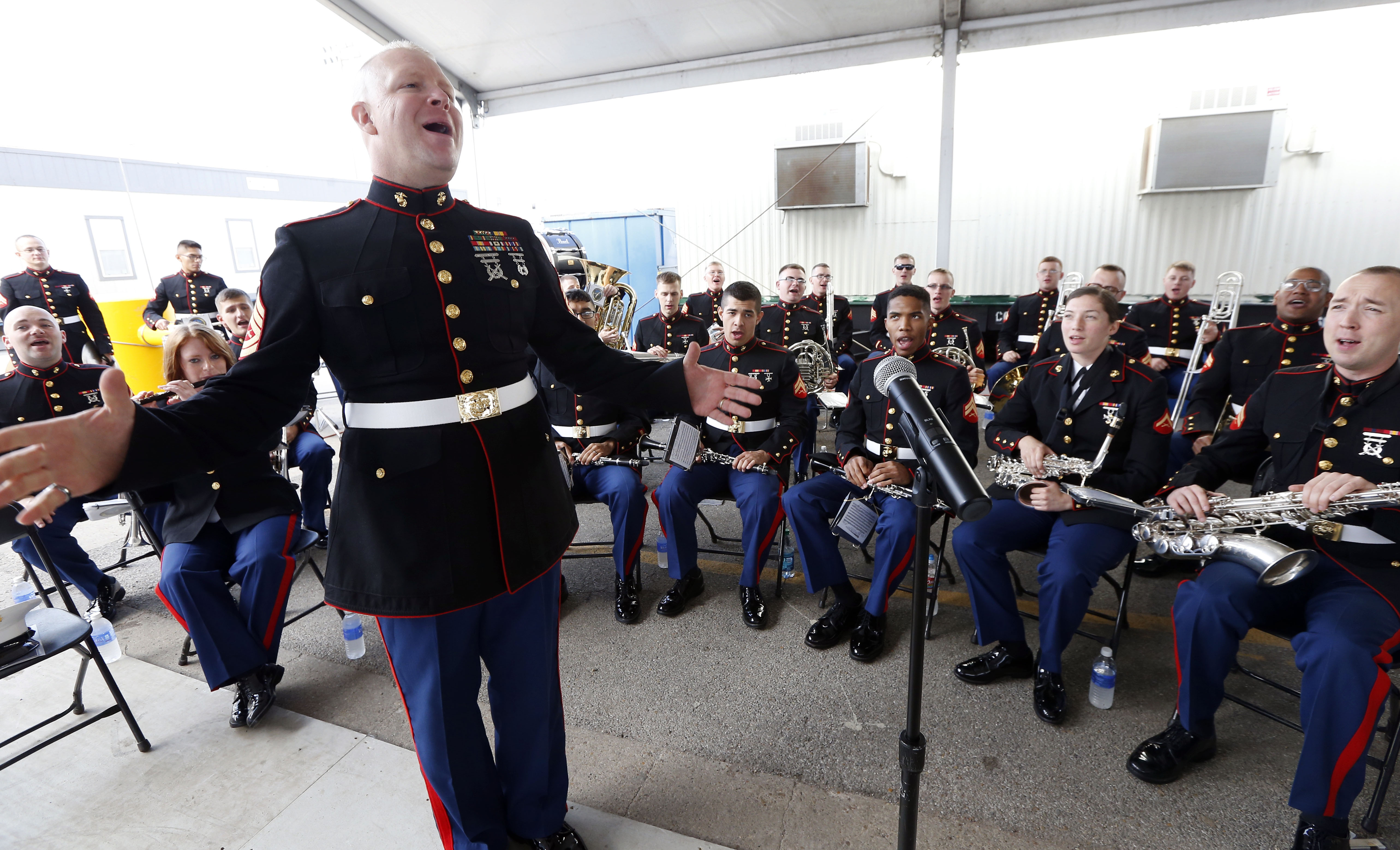 Enlisted Conductor Gunnery Sgt. Michael Maschmeier, leads the U.S. Marine Corps Band from New Orleans in singing prior to the christening  amphibious transport dock, the John P. Murtha  in 2015. (AP Photo/Rogelio V. Solis)