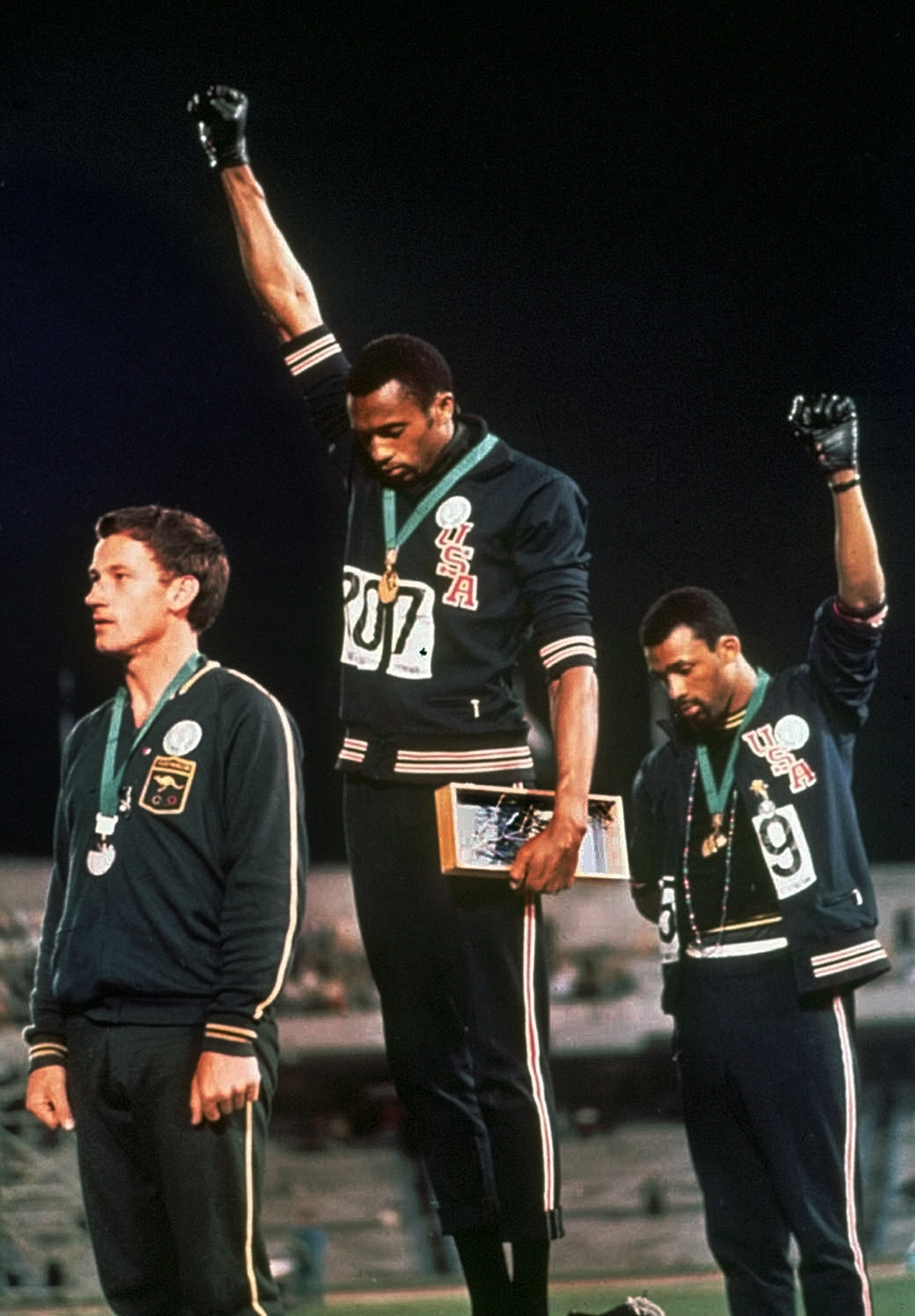  Extending gloved hands skyward in racial protest, U.S. athletes Tommie Smith, center, and John Carlos stare downward during the playing of the Star Spangled Banner after Smith received the gold and Carlos the bronze for the 200 meter run at the Summer Olympic Games in Mexico City on Oct. 16, 1968. AP Photo/FILE.