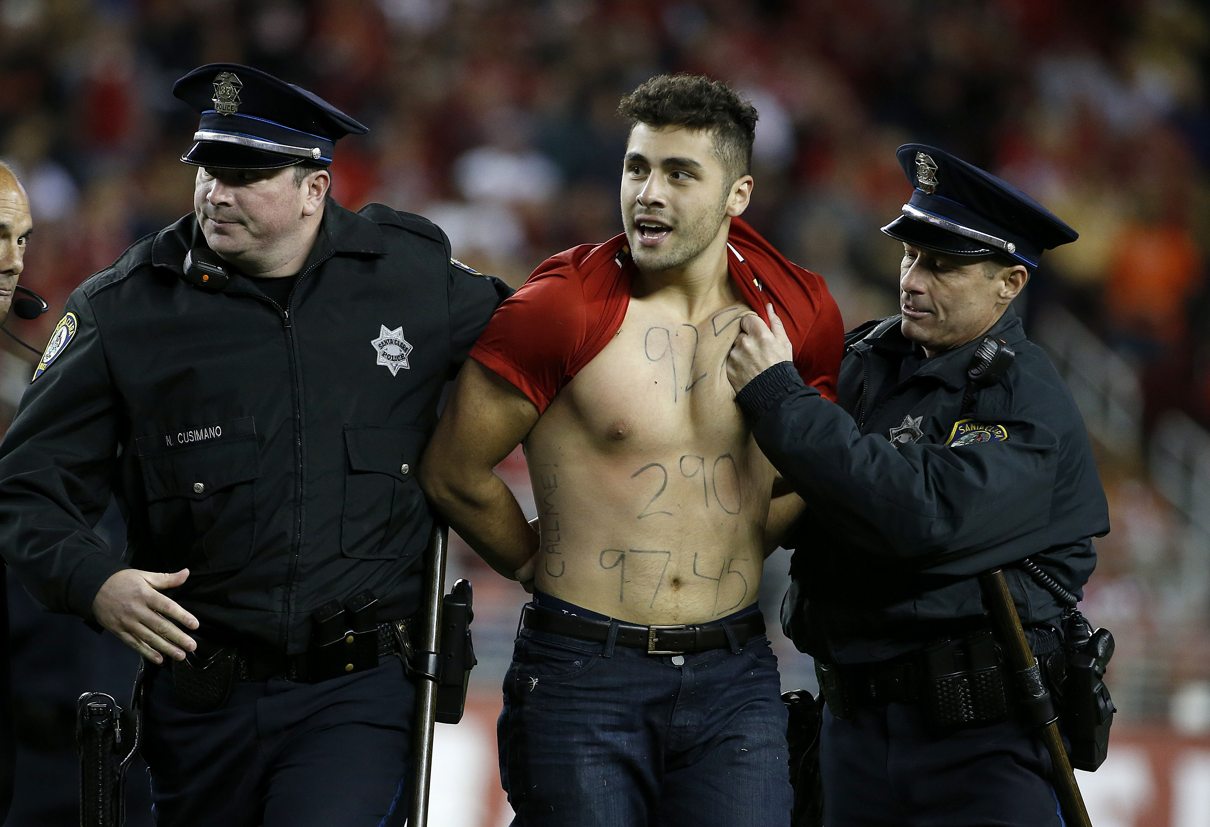 A fan is taken off the field by Santa Clara police officers during the second half of an NFL football game between the San Francisco 49ers and the Los Angeles Rams in Santa Clara, Calif., Monday, Sept. 12, 2016. (AP Photo/Tony Avelar)