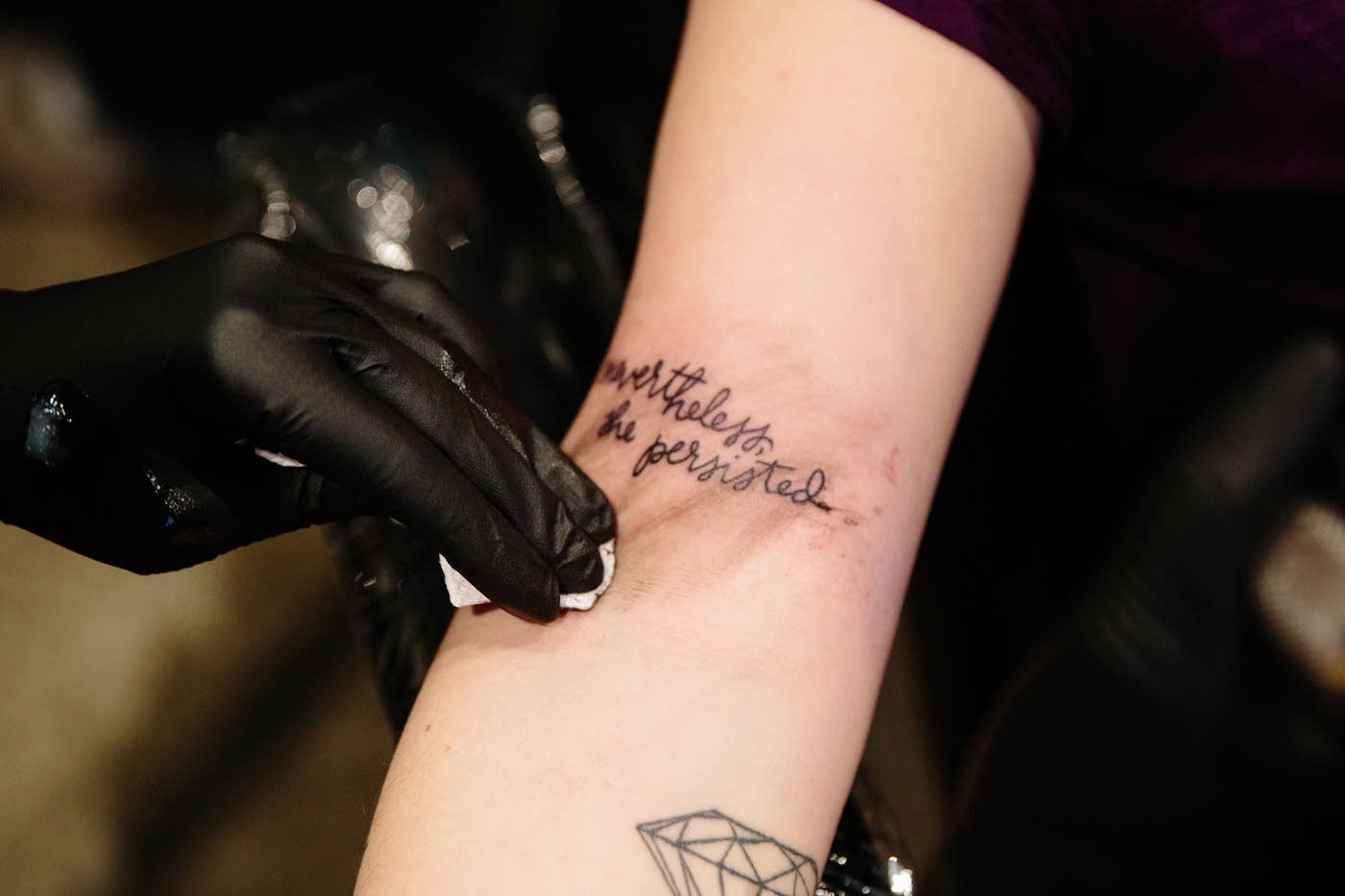 A fresh "nevertheless, she persisted" tattoo is wiped clean inside Brass Knuckle Tattoo Shop. Evan Frost | MPR News